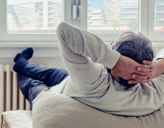 Mann sitzt entspannt vor einer Heizung