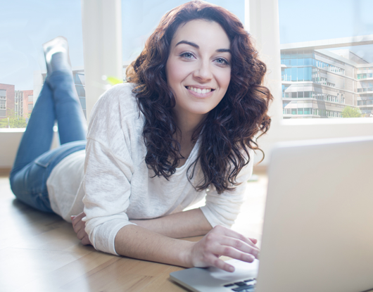 Eine junge Frau schaut von ihrem Laptop auf.