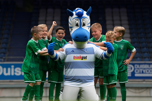 Kinder in Trikots posieren mit dem MSV-Maskottchen