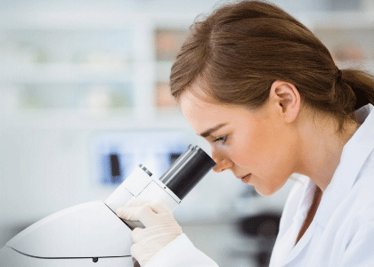 Wissenschaftlerin schaut durch ein Mikroskop