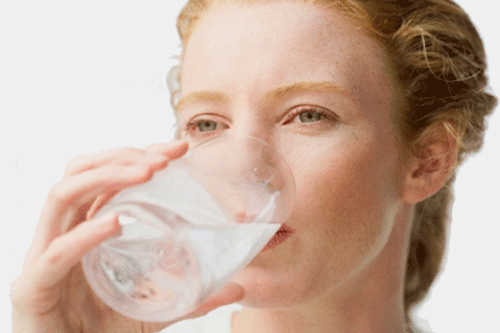 Frau trinkt Wasser aus einem Wasserglas