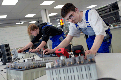 Zwei Auszubildende überprüfen eine elektronische Anlage